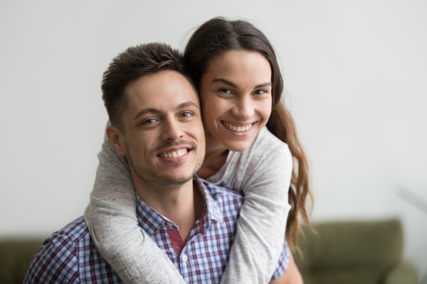 smiling_man_piggyback_cheerful_wife_looking_camera